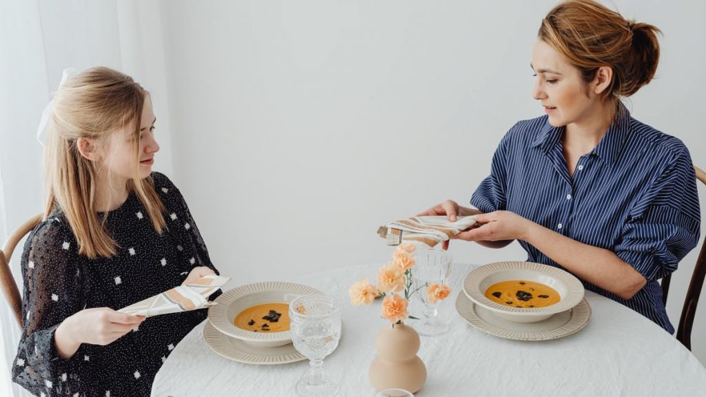 Two women dining with soup at an elegantly set table.